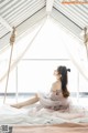 A woman sitting on a bed in a tent.