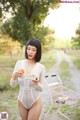 A woman in a white bodysuit holding a plate of food.