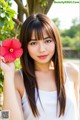 A woman holding a red flower in her hand.