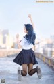 A woman in a school uniform is dancing on a rooftop.