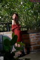 A woman in a red dress standing next to a brick wall.