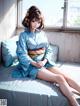 A woman in a blue kimono sitting on a bed.