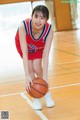 A woman in a red and blue uniform holding a basketball.