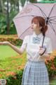 A woman in a school uniform holding an umbrella.