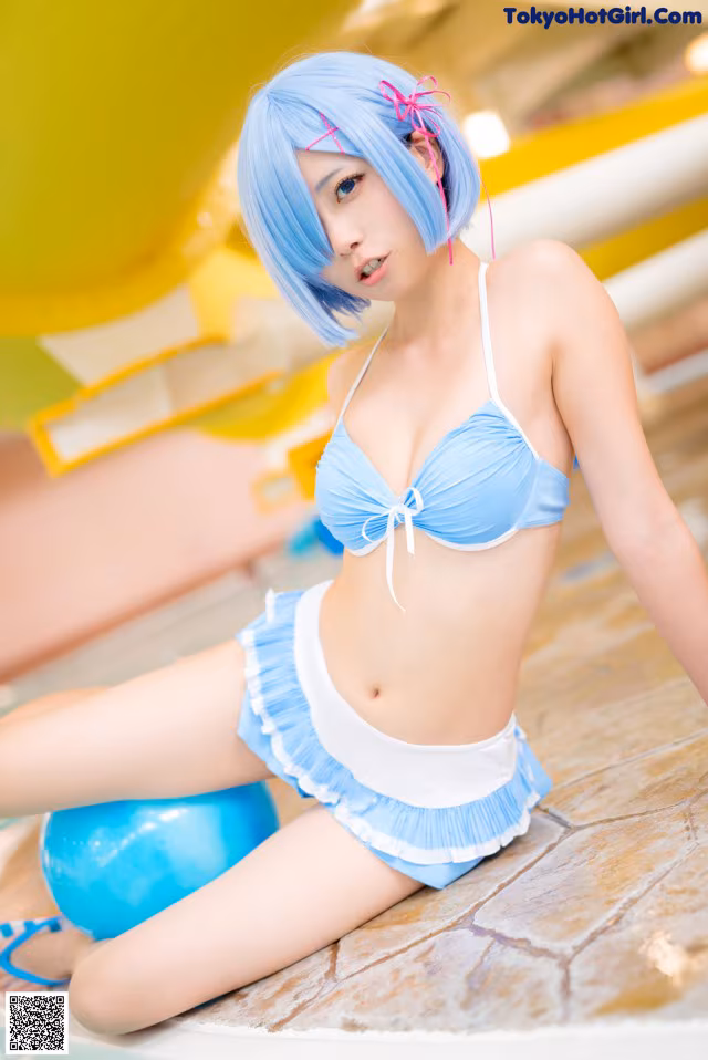 A woman in a blue bikini sitting on a blue ball.