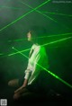 A woman sitting on the ground in front of a green laser light.